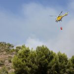 Helicóptero lança água sobre uma área atingida por um incêndio florestal na Espanha.