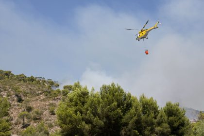 Helicóptero lança água sobre uma área atingida por um incêndio florestal na Espanha.