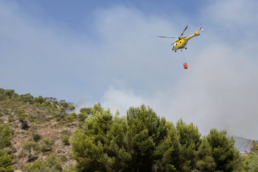 Helicóptero lança água sobre uma área atingida por um incêndio florestal na Espanha.