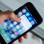 Pessoa anônima usando um aplicativo no celular para consultar opções na tela.