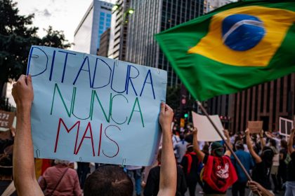 Manifestantes participam de ato em São Paulo, no Brasil, segurando cartazes sobre direitos humanos e democracia.